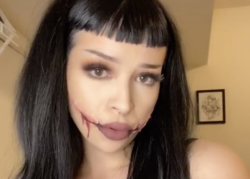 A woman wears makeup to appear that she has cuts coming from both sides of her lips