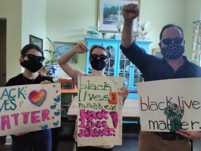 Three white people holding "black lives matter" signs