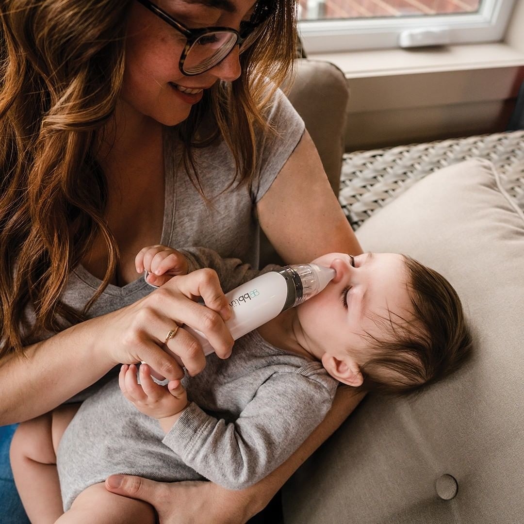 A person using an electric nasal aspirator on their baby's nose