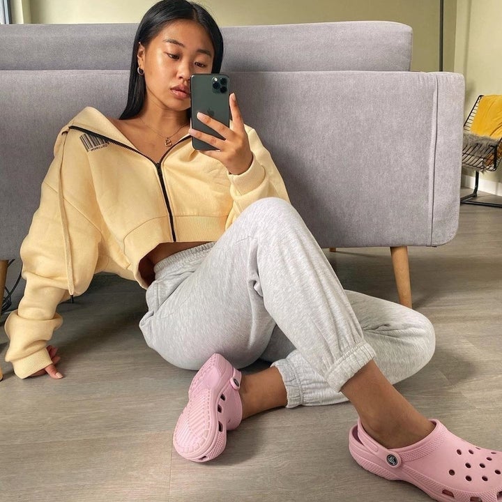 a model wearing pink crocs and cozy clothing
