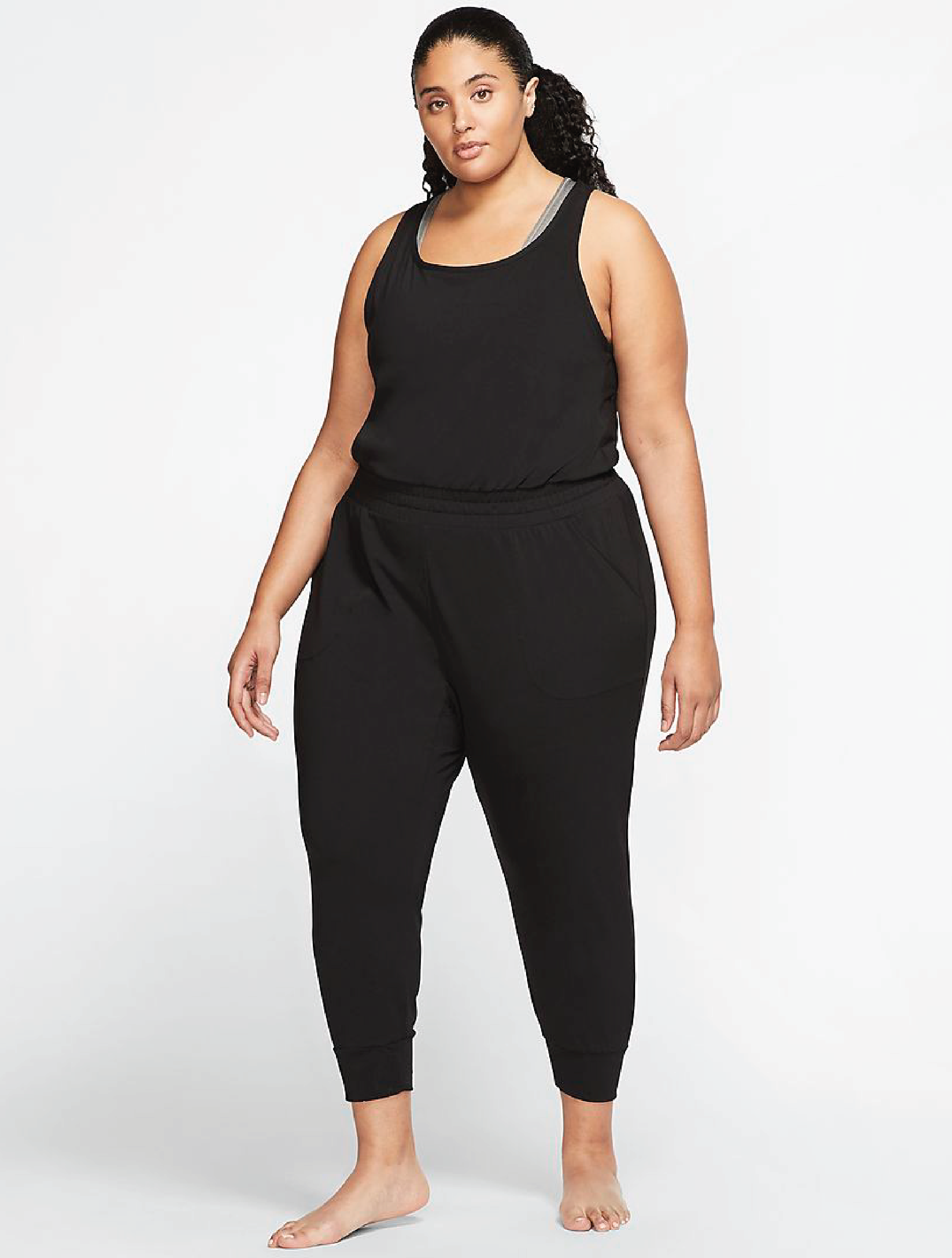 A plus sized model wearing the black jumpsuit