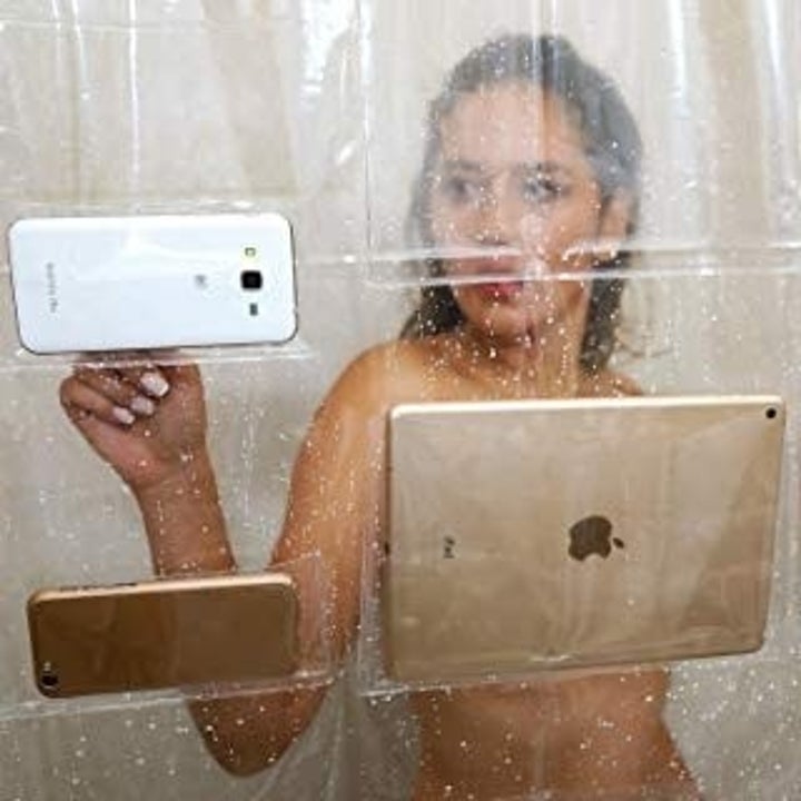 close-up of a model watching a tablet being held up by in the shower curtain. There are also two cell phones in different slots too. 
