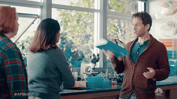 A gif of Colin and Sarika watching Jack throw a textbook out the window