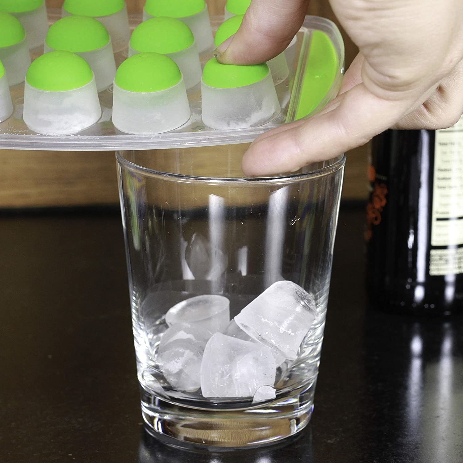 A person putting ice cubes into a glass cup