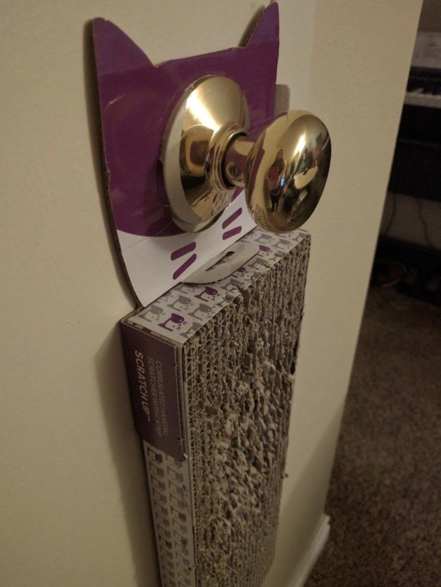 A cardboard cat scratcher handing on a bedroom doorknob