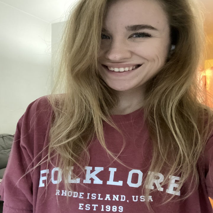 buzzfeed editor wearing the red tee with folklore written on it in white and "rode island, usa est 1989"