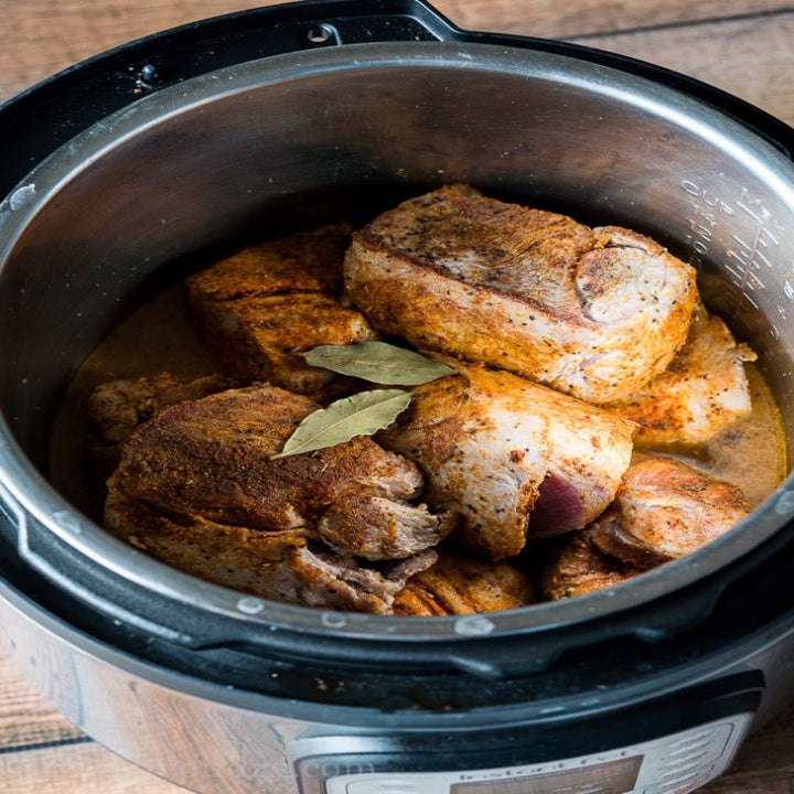 An Instant Pot with marinated, spice-rubbed pork shoulder inside.