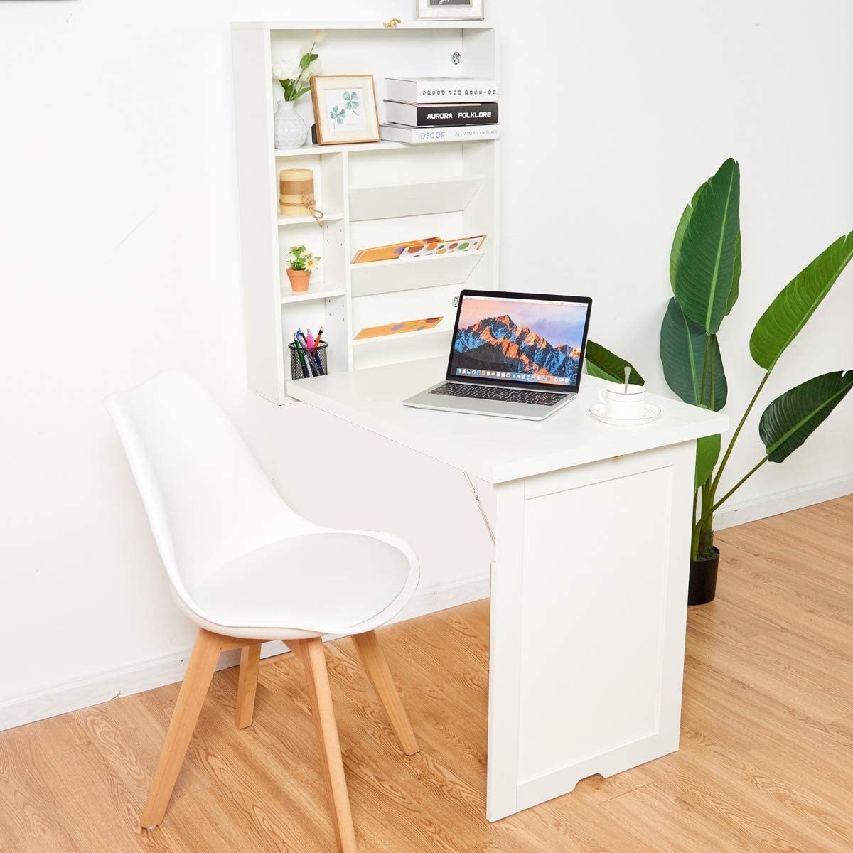 the table mounted to a wall and folded down with a laptop on it 