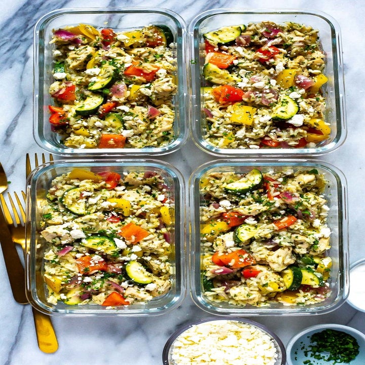 Four storage containers filled with Greek chicken, veggies, and rice 