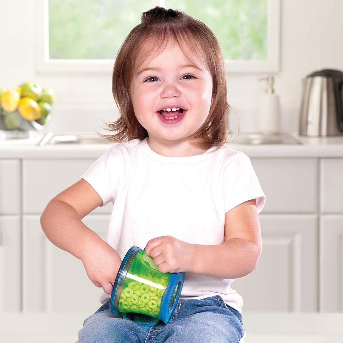 A small child holding a small bowl filled with Cheerios