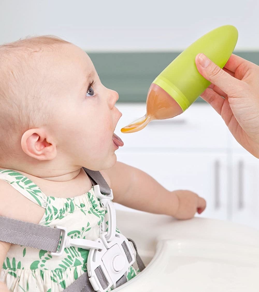 Baby being spoon fed with squeezable spoon that has food inside 