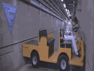 Austin Powers driving a cart back and forth in a hallway
