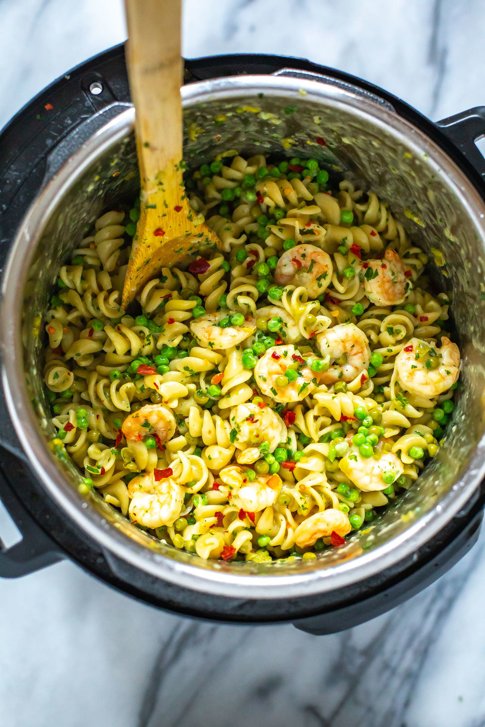 An Instant Pot filled with pasta, shrimp, peas, and red pepper flakes.