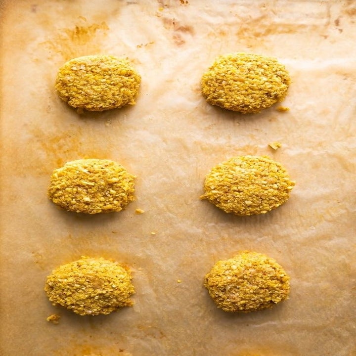 Six crispy falafel on a baking sheet lined with parchment paper.