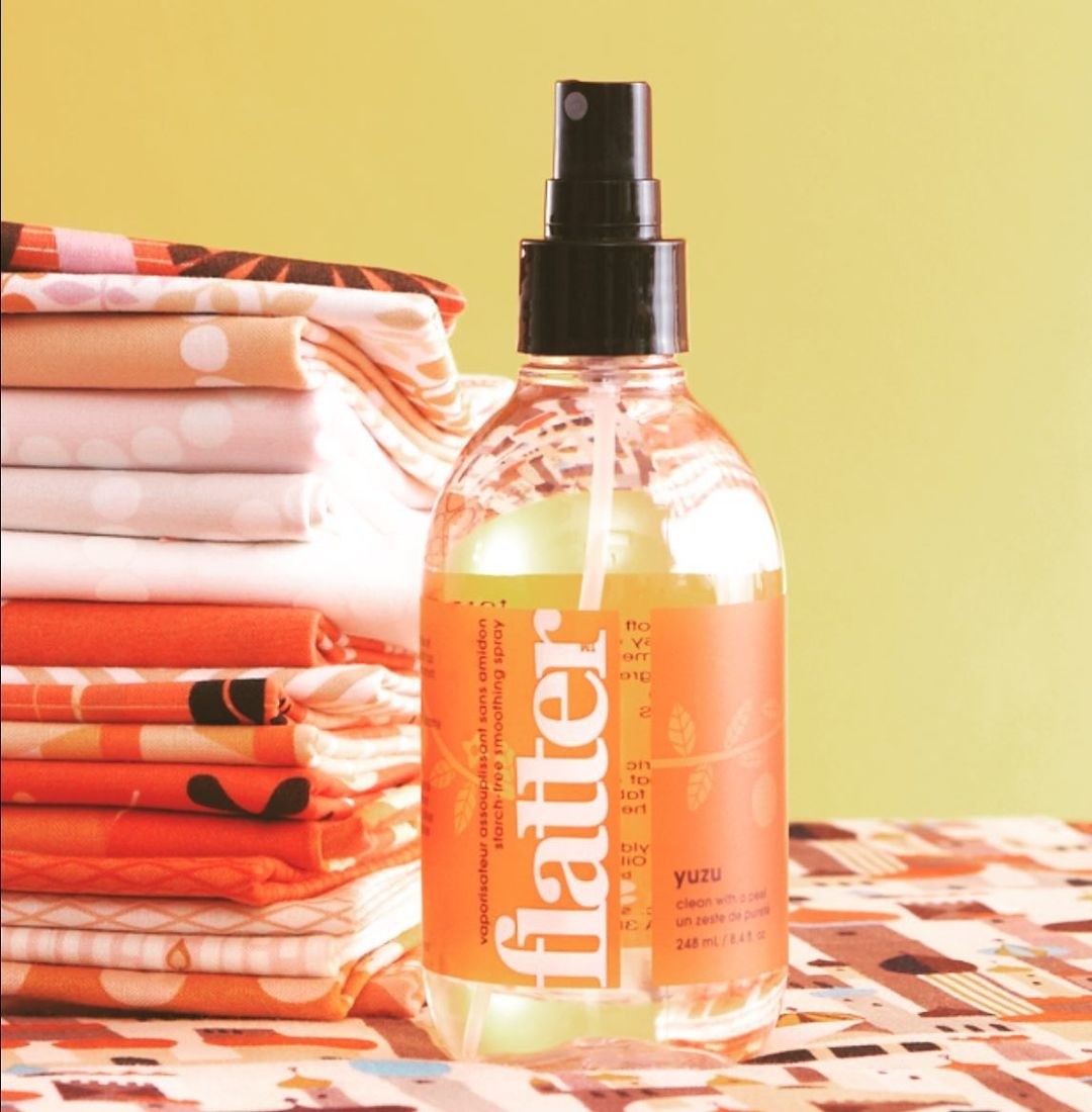 A bottle of spray next to folded linens
