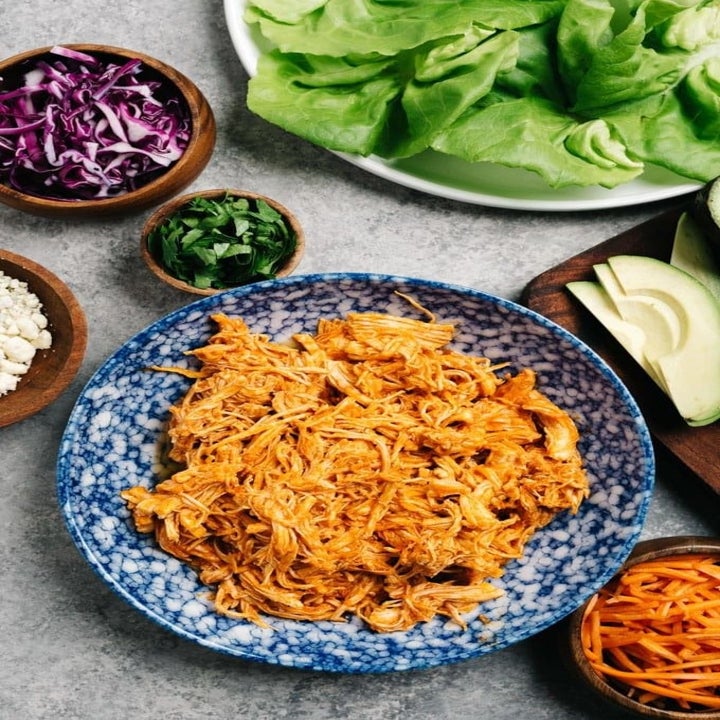 Ingredients for lettuce wraps including buffalo chicken, Boston lettuce, cabbage, and scallions.