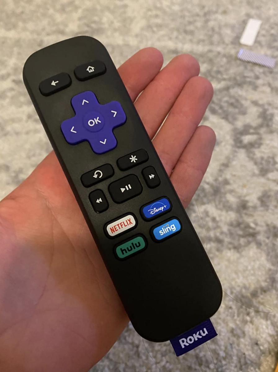 A reviewer holding the Roku remote