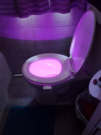 reviewer's toilet light glowing in purple 