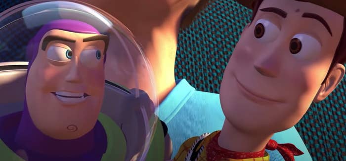 Buzz Lightyear and Woody smiling at each other while sitting in Andy&#x27;s lap