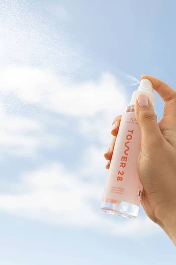 model holding the clear spray bottle with white cap labeled 