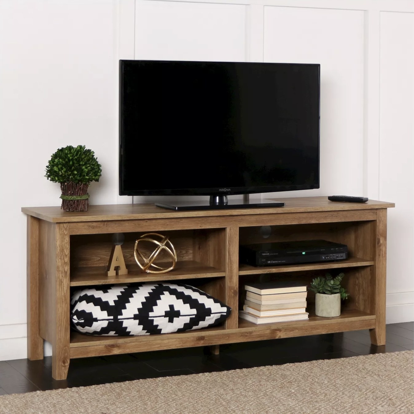 A wood TV stand with a TV on top and decor in the shelves