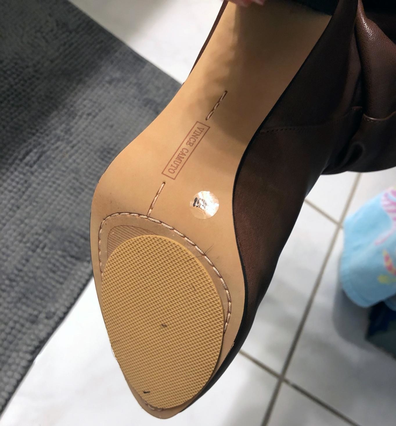 A reviewer showing the bottom of their heeled pump shoe with the sole placed on it