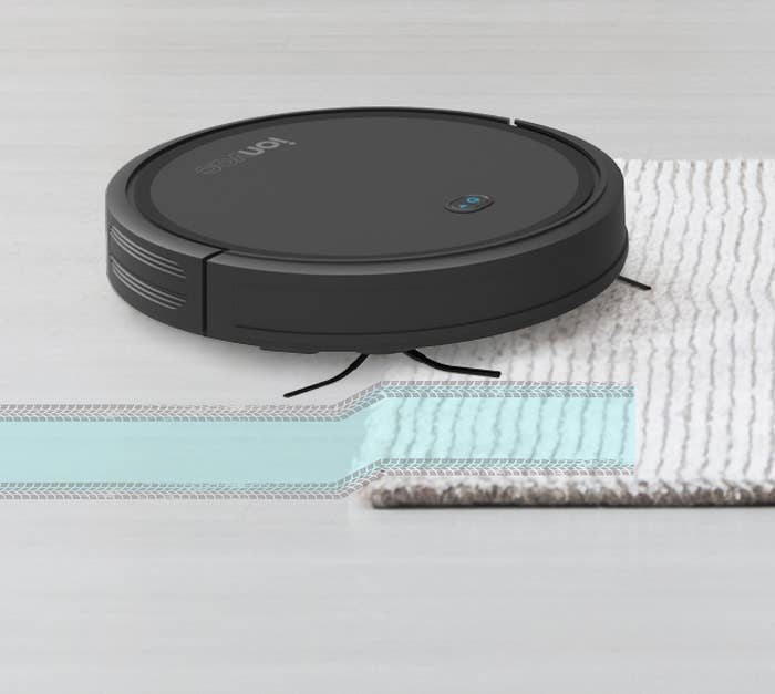 robot vacuum going over a rug on a hard floor