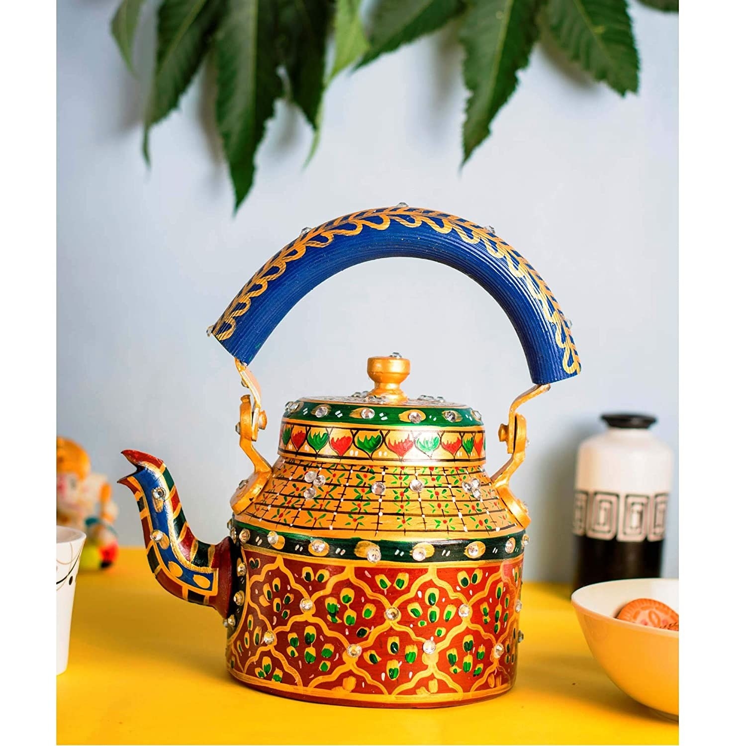 An aluminium kettle painted with an intricate design in shades of red, yellow, green, and royal blue.