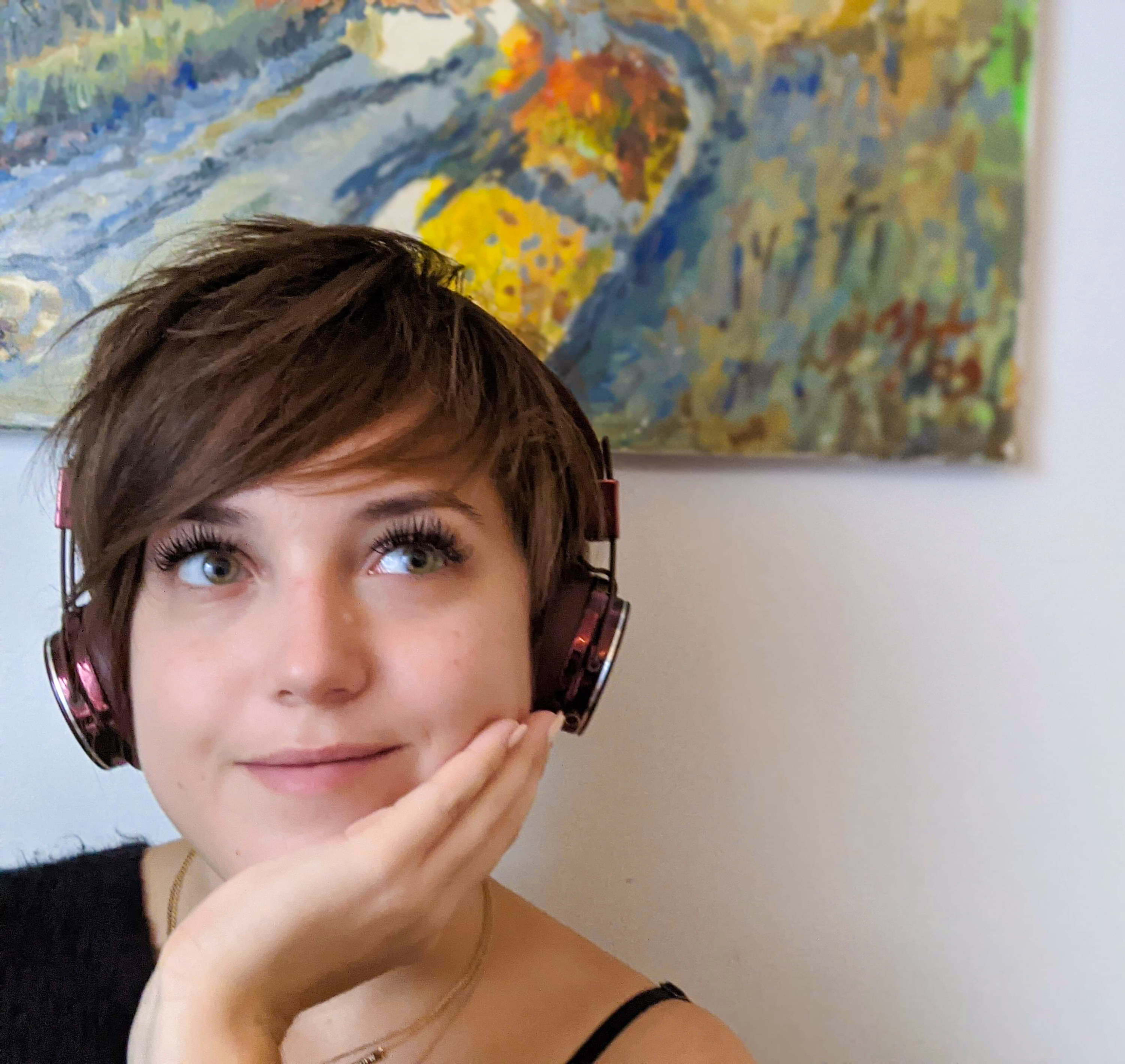 A smiling person wearing the over the ear headphones while looking off-camera