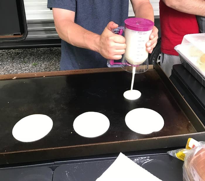A model using a pancake dispenser to dispense even circles of pancake batter on top of a griddle