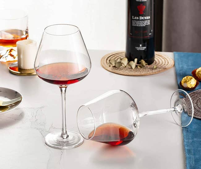 A set of two deep glass long-stemmed wine glasses with red wine 