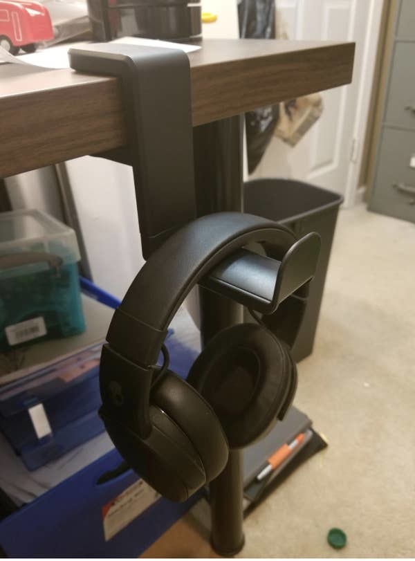 a pair of headphones hanging from the holder off a desk