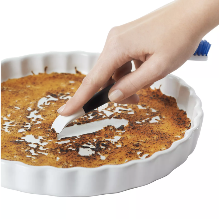 the opposite end of one of the brushes being used to scrap a dirty dish 