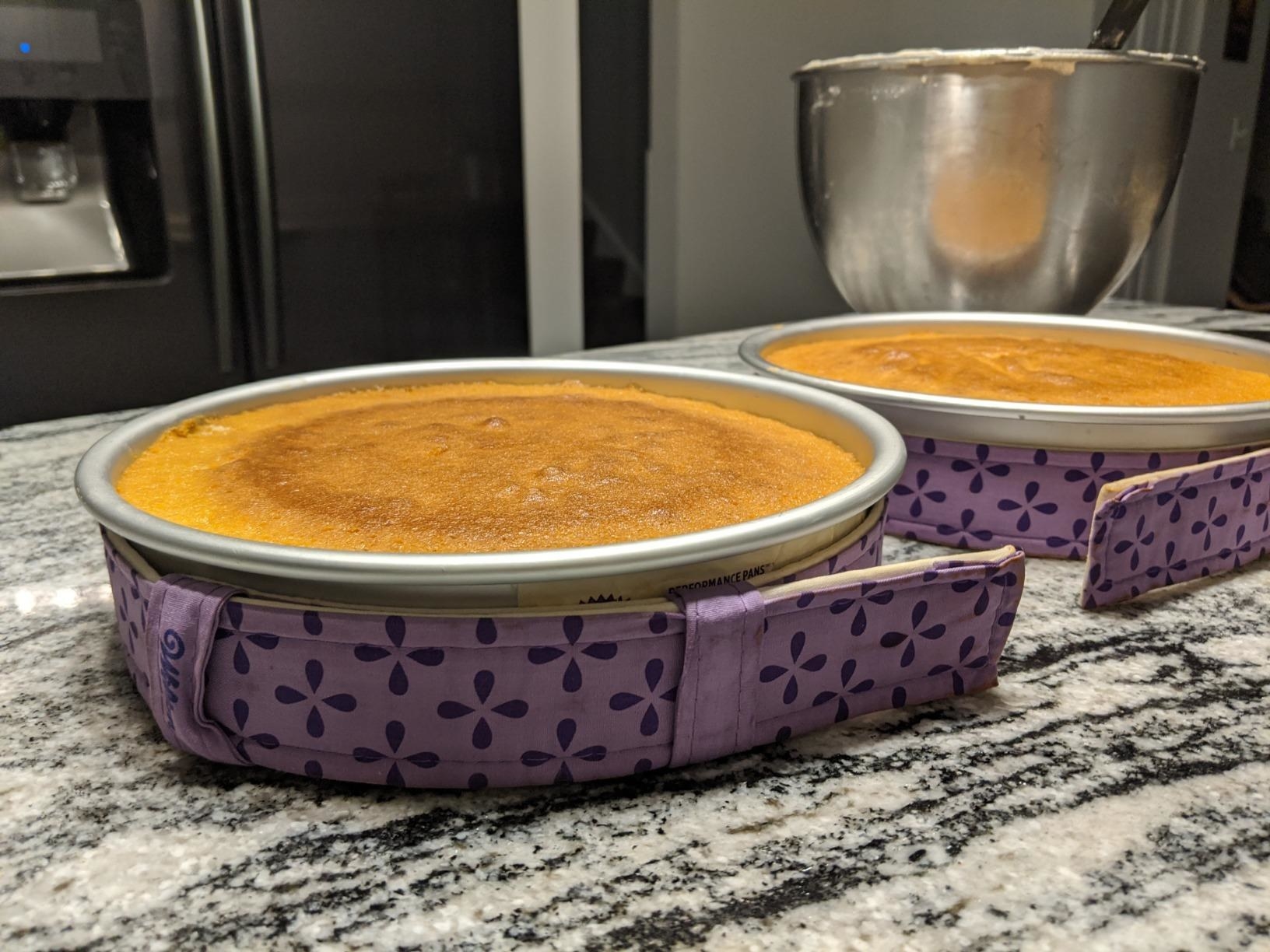 Two cake pans with purple fabric cake pan strips wrapped around the sides