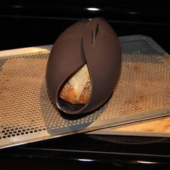Bread maker placed on pan inside the oven with baked bread visible from the side