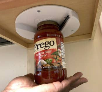 Reviewer using the opener to open a jar of sauce with just the palm of their hand