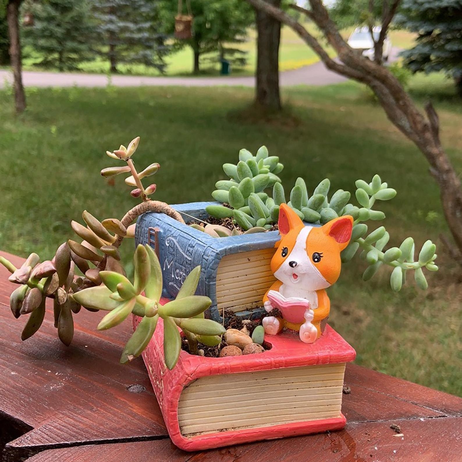 Mini planter of two stacked books with dog reading a book on the side 