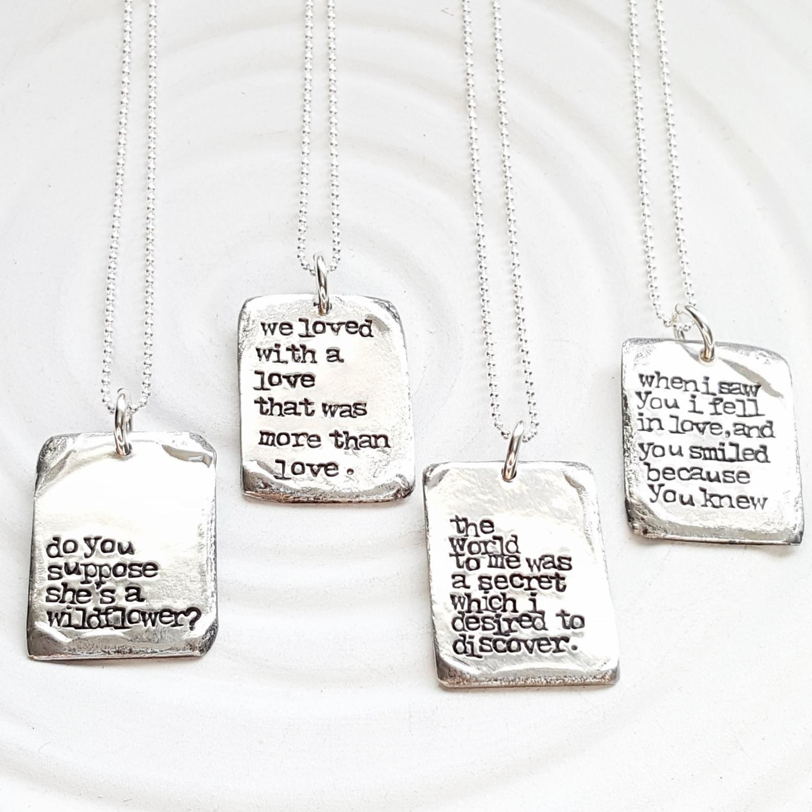 Four pewter pendants with different literary quotes stamped on them 