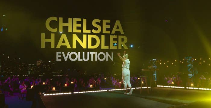 Chelsea Handler on stage in front of a socially distanced audience with the NYC skyline in the background, and the words &quot;Chelsea Handler Evolution&quot;