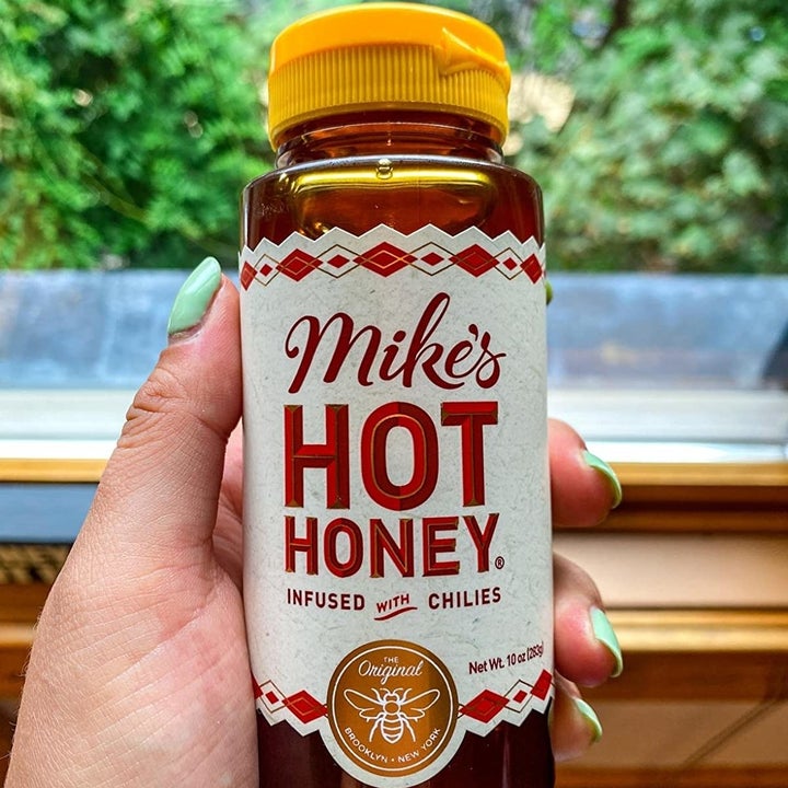 A hand holding a bottle of Mike's Hot Honey
