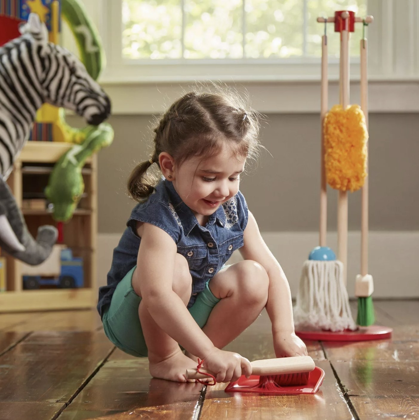 A child playing with a toy brush and dustpan