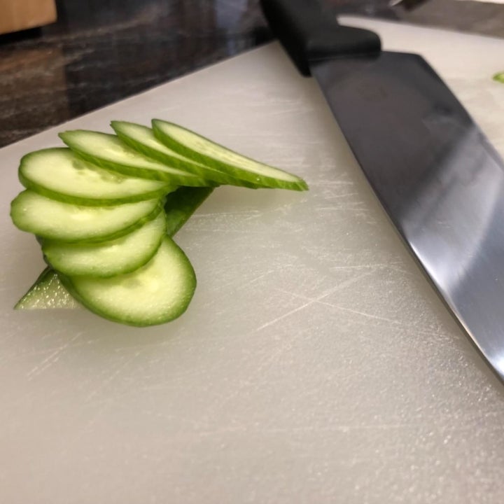 Sliced cucumbers next to a chef's knife