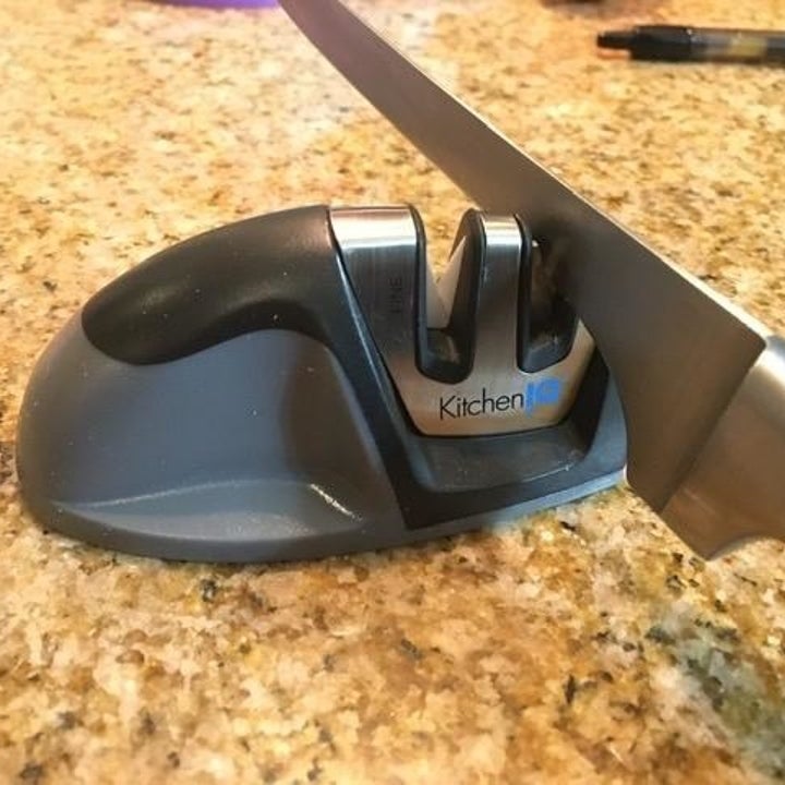 A knife inserted into one of two slots on a knife sharpener.