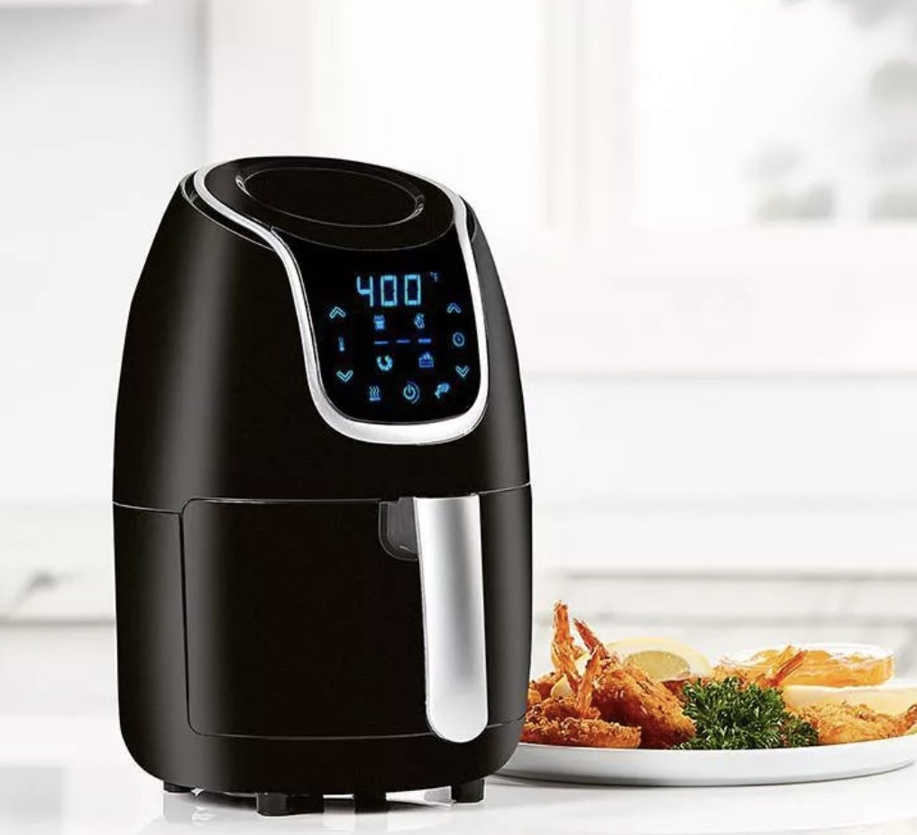 A black air fryer next to a plate with fried food