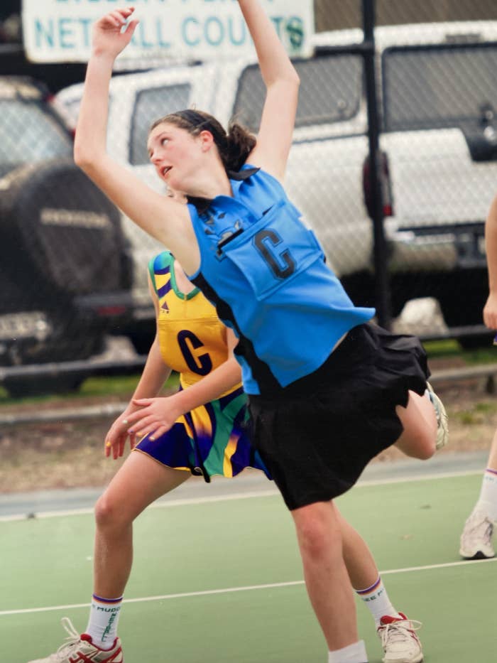 Girl playing centre leans over opponent trying to intercept the ball