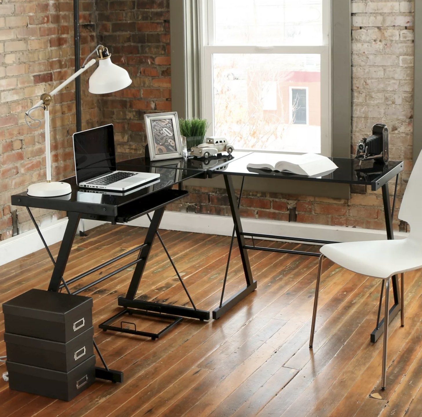 A black L-shaped computer desk in a living space