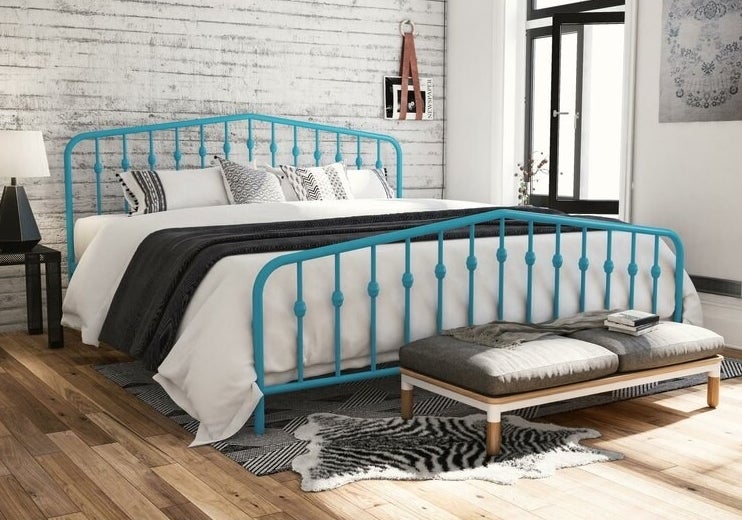 The bed frame, which has a headboard and footboard, each made from slatted colored metal