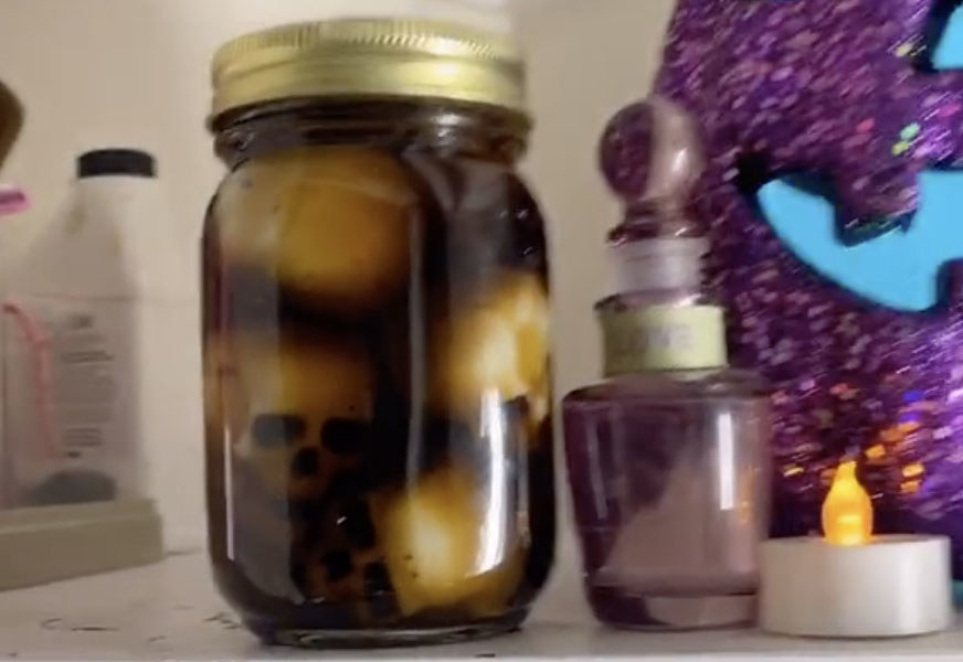Skulls sit in a large jar filled with a black liquid 