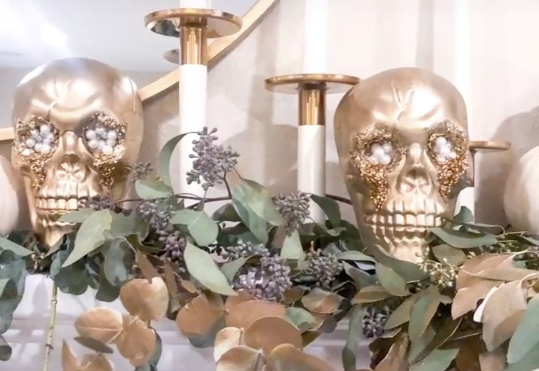 Skulls painted with gold and glitter sit on a mantle 