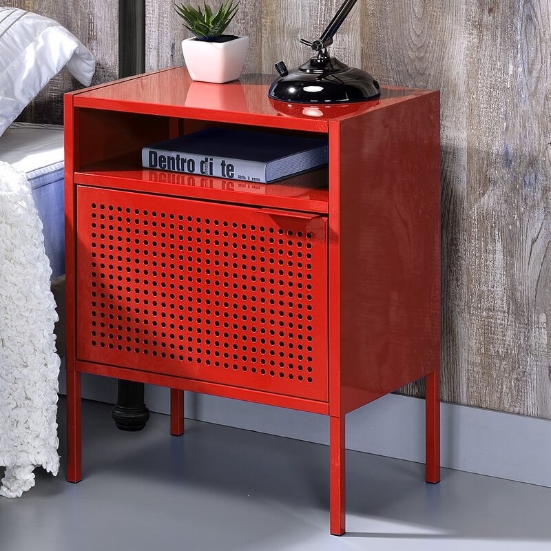 The nightstand in red, with two storage areas — an open storage area at the top of the nightstand, and a cabinet-style storage area in the bottom half, which has a perforated metal door